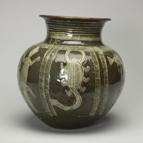 A green ceramic stoneware water jar. It is decorated with animals. This side shows a lizard, scorpion and fish.