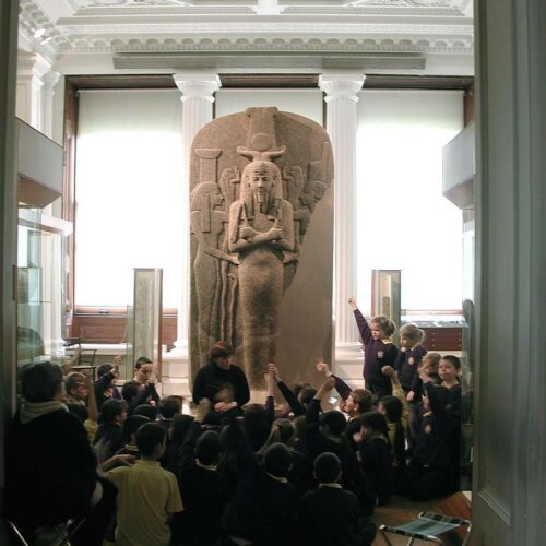 A school class learning in the ancient Egyptian galleries, in front of the large coffin lid of King Ramesses III