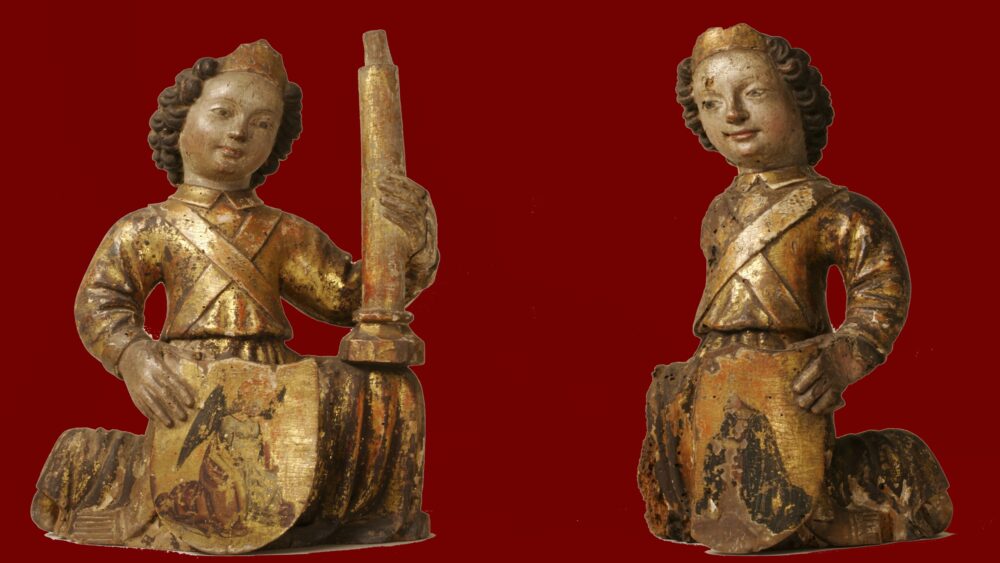 Two small wooden angels, kneeling and facing each other.