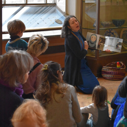 Children and adults listen to a story in the museum gallery